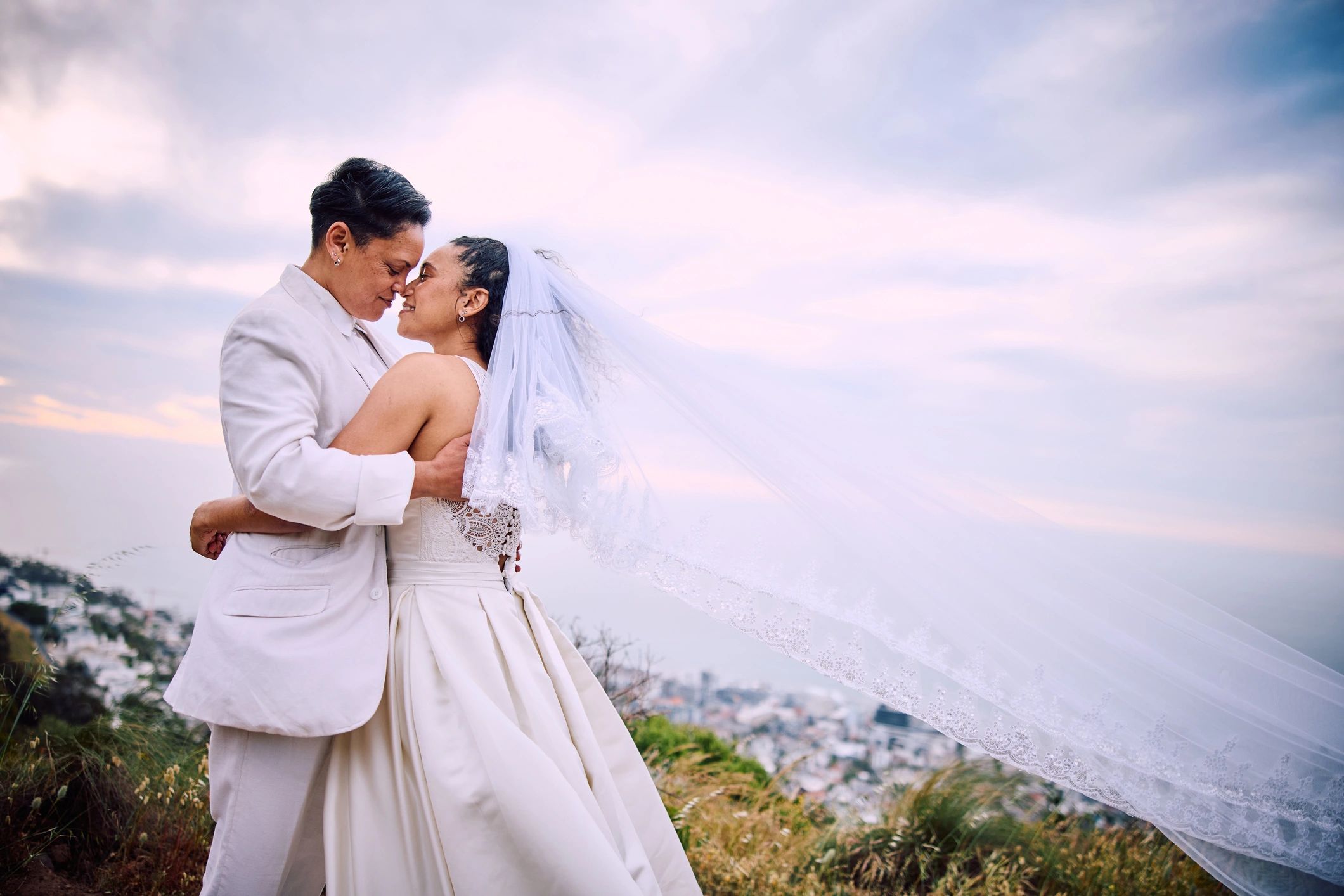 Newlywed couple sharing a kiss outdoors during a wedding celebration